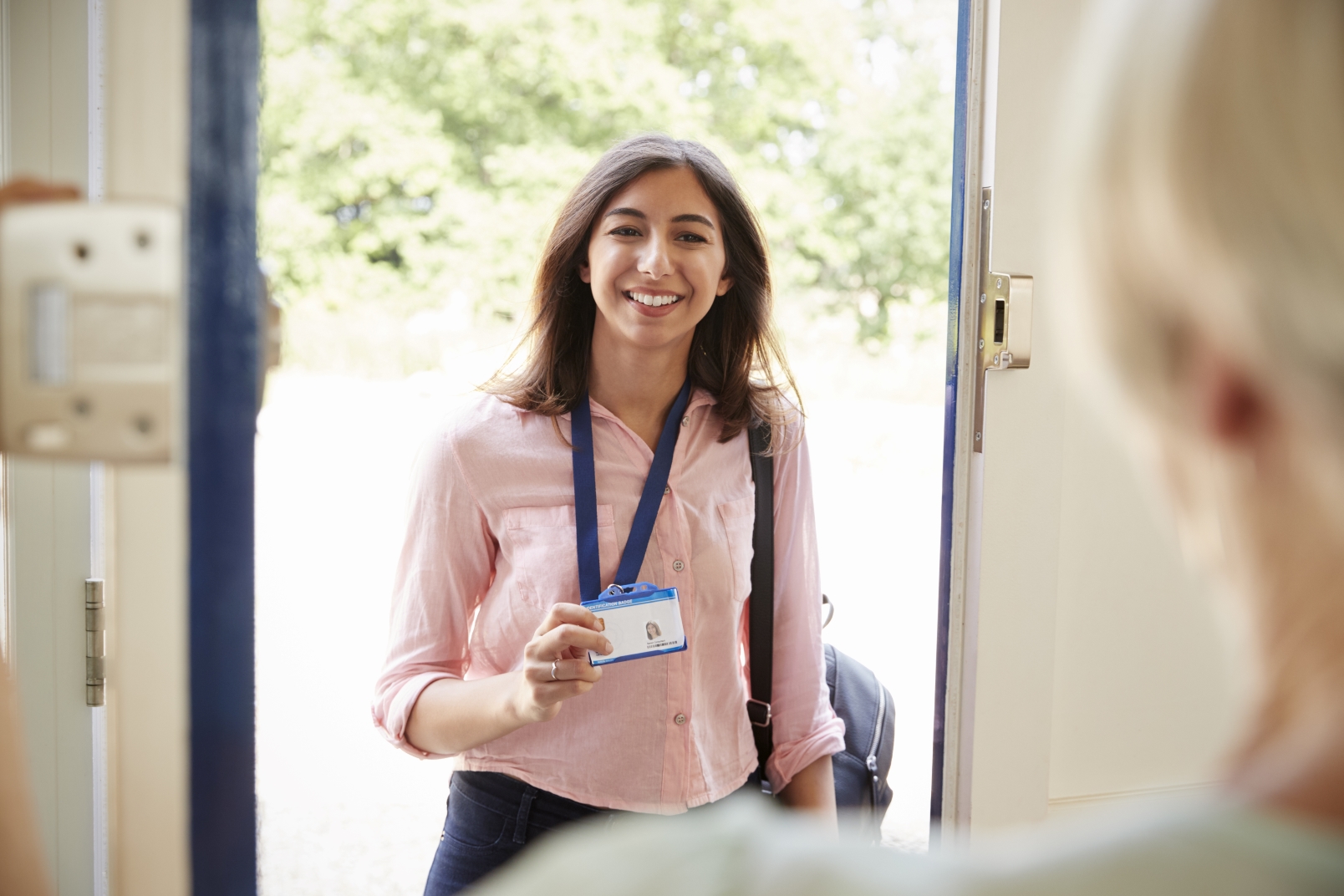 Professional woman entering a home showing her ID card